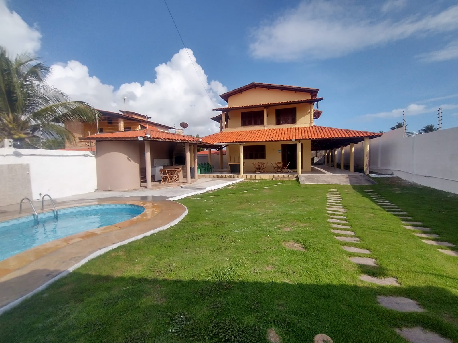 Vista da casa de praia com piscina e jardim